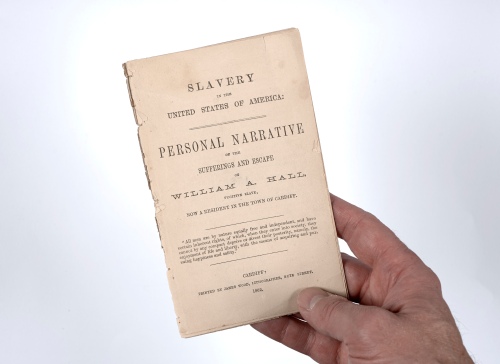 hand holding a pamphlet named 'Slavery in the United States of America, a Personal Narrative'